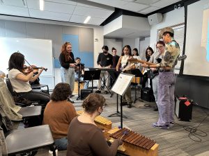 Rebecca leading a session of Thriller with NYU students playing various percussion, keyboard instruments and violin