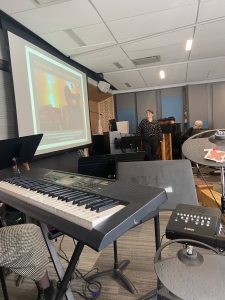 Emma presenting to students in front of a screen with instruments in the foreground